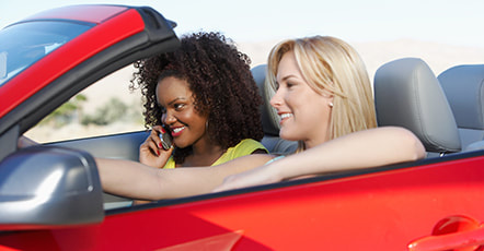 Two young adult ladies sitting in front of the car photo